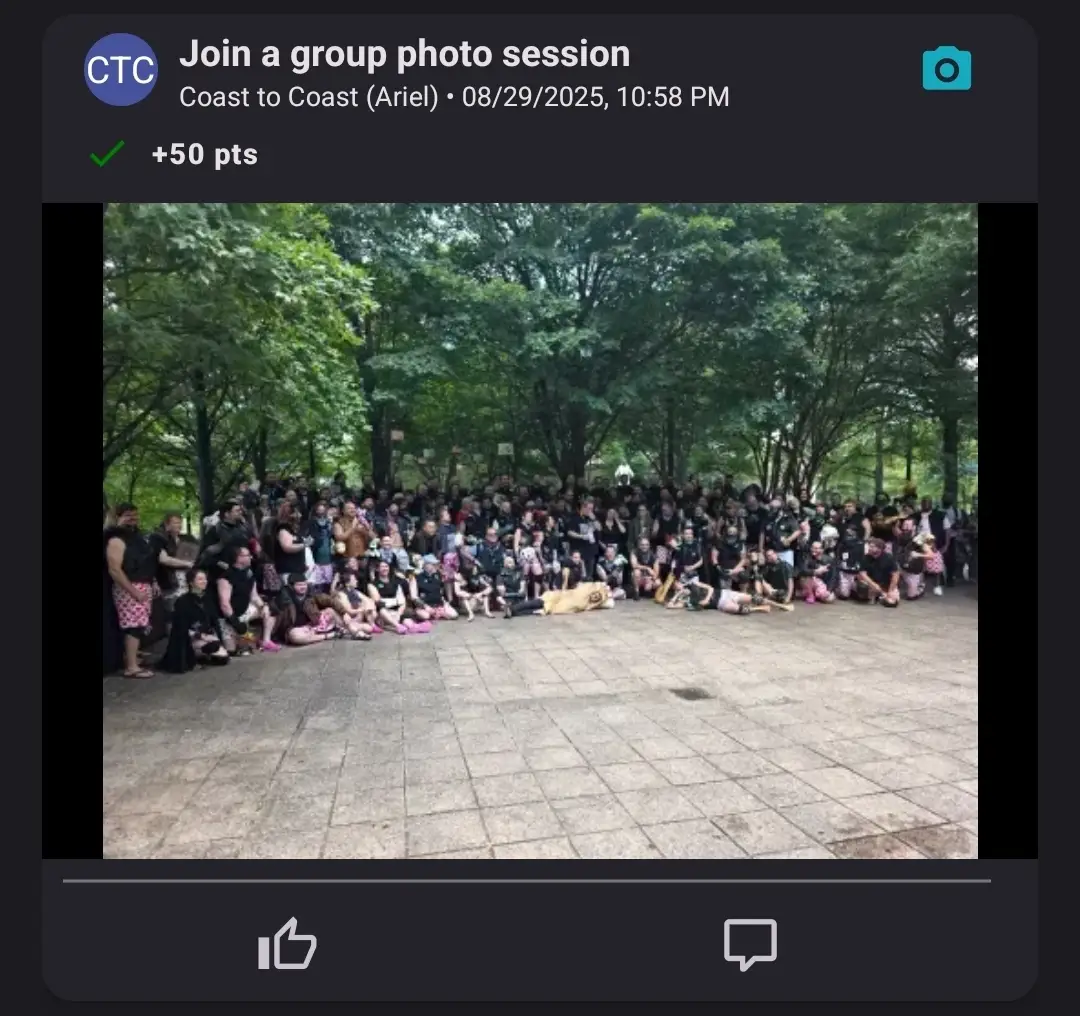 A large crowd posing together for a group photo in a park with trees in the background